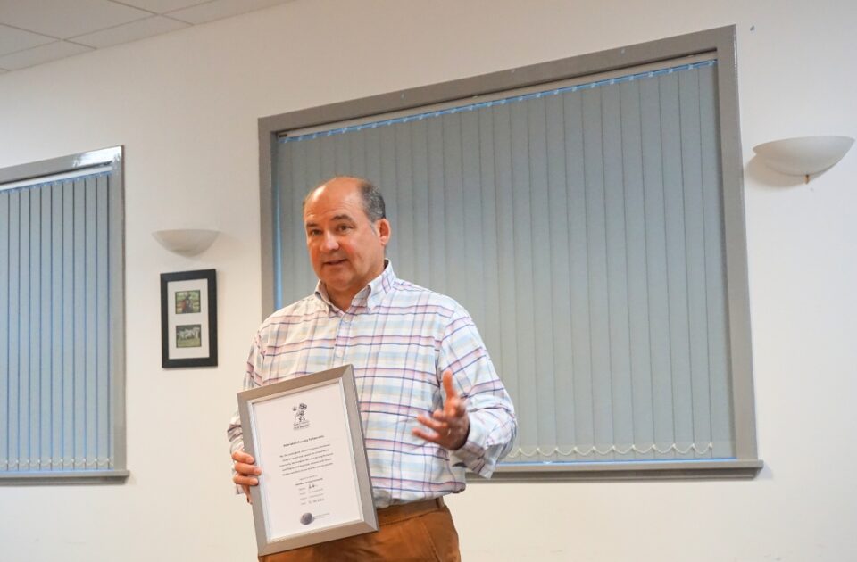Ray Watt holding certificate and explaining to audience about the Armed Forces Covenant.